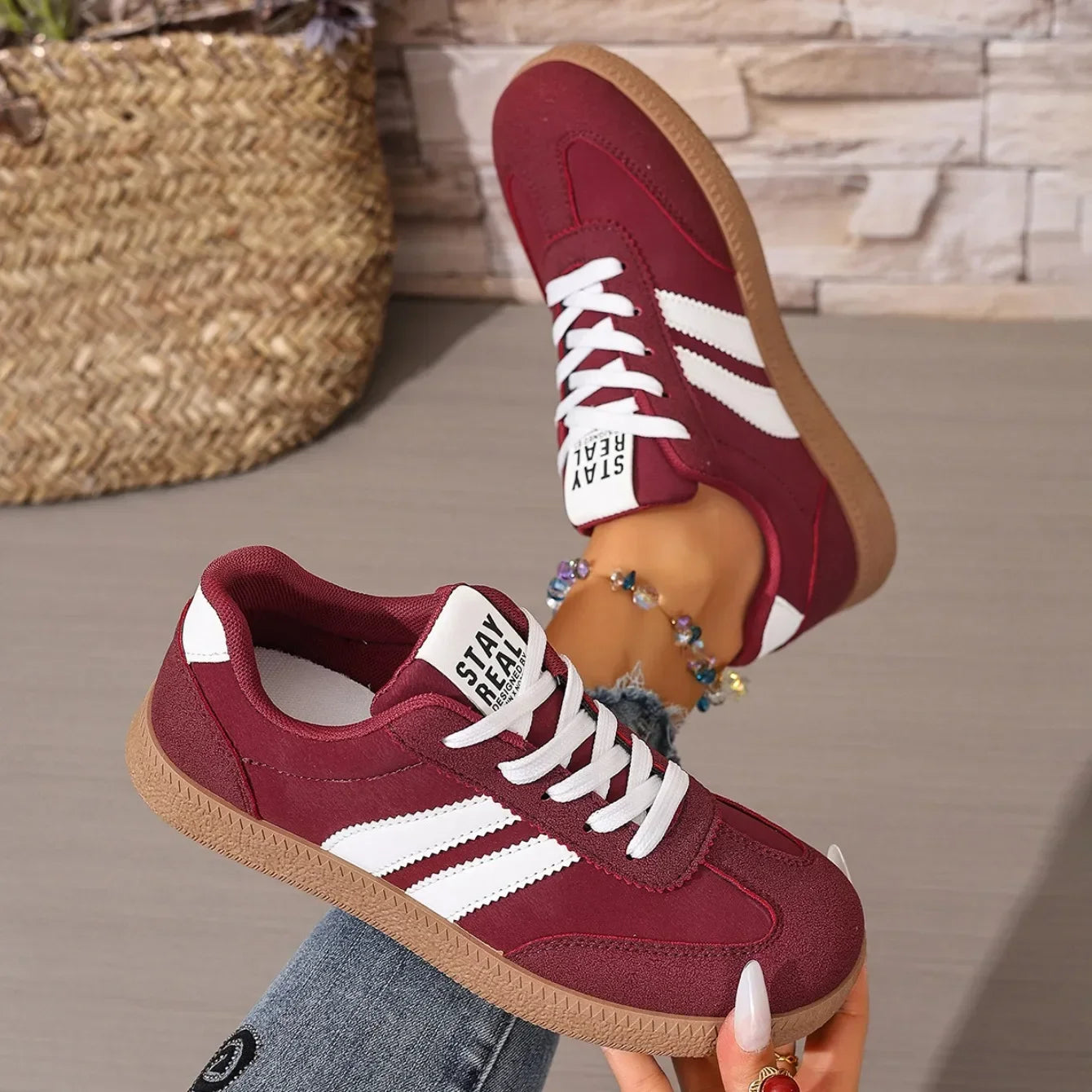 Maroon leather slip-on sneakers with white stripes and gum soles for casual daily wear.