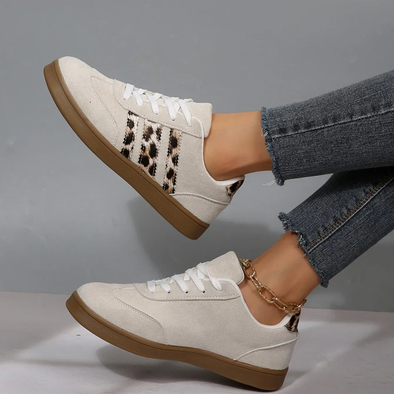 Beige suede slip-on sneakers with leopard print stripes and brown rubber soles for casual everyday wear.