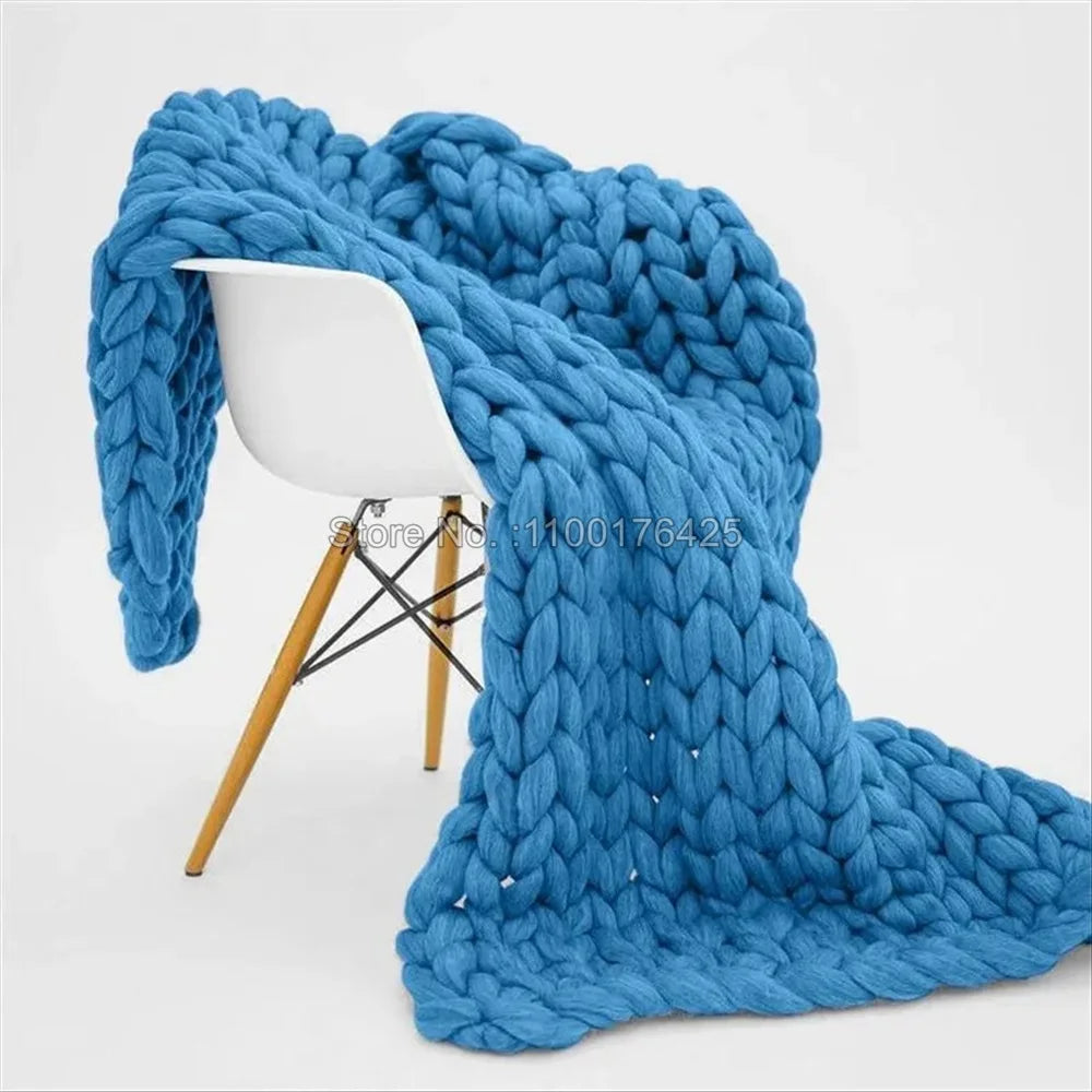 Bright blue chunky knit throw blanket draped over a white modern chair.