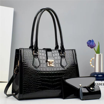 Black patent leather crocodile-pattern tote bag with gold clasp, top handles, and two matching wallets.