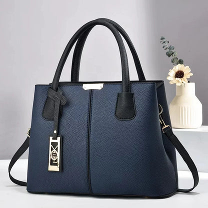 Navy blue faux leather structured tote bag with black handles, gold charm, and zip closure for everyday use.