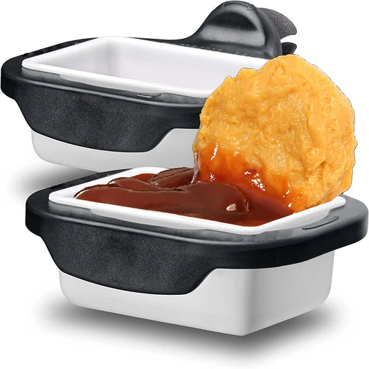 Two black and white car vent sauce holders, one holding barbecue sauce and a nugget.