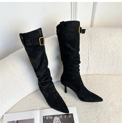 Black suede knee-high boots with pointed toes, thin heels, and gold-buckled ankle straps.
