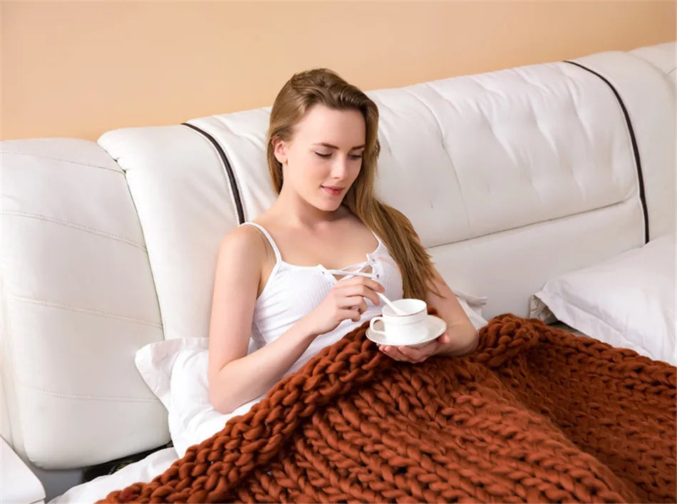 Brown chunky-knit roving blanket made of thick yarn, draped over a person in bed.