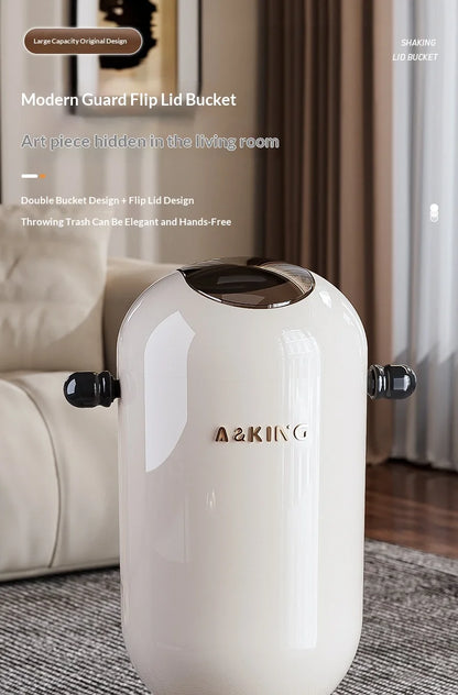 Glossy white rounded trash can with a dark swing lid and handles, featuring gold lettering on the front.