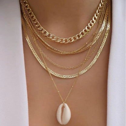 Gold-tone layered chain necklace set with a white cowrie shell pendant for a bohemian jewelry accessory look.