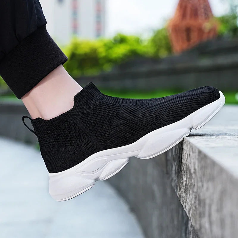 Black slip-on moccasin sneakers with a breathable knit upper and white sole for casual daily wear.