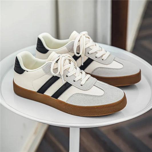 White and grey canvas sneakers with black stripes, suede details, and gum soles. Breathable casual training shoe for gym.