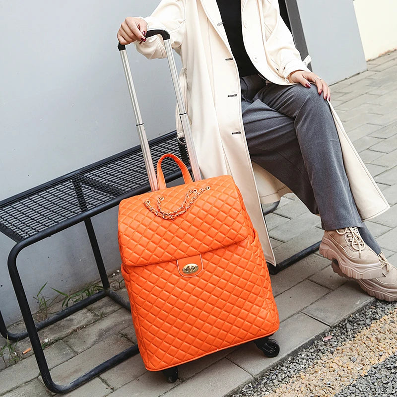 Bright orange quilted PU rolling suitcase with a top handle, turn-lock closure, chain detail, and telescoping handle.
