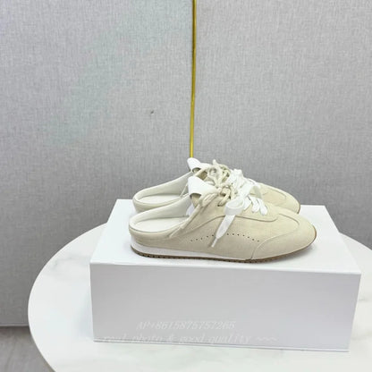 Beige suede slip-on shoes with round toes, white laces, and flat soles.
