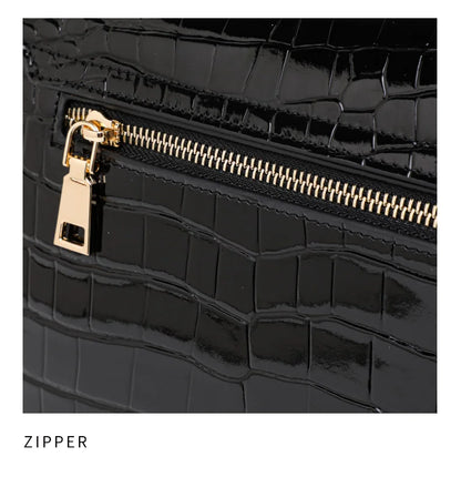 Black patent leather handbag with crocodile pattern, featuring a gold zipper and pull tab.
