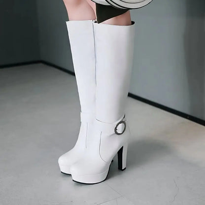 White knee-high platform boots in faux leather with a high heel, round toe, and ankle buckle strap.