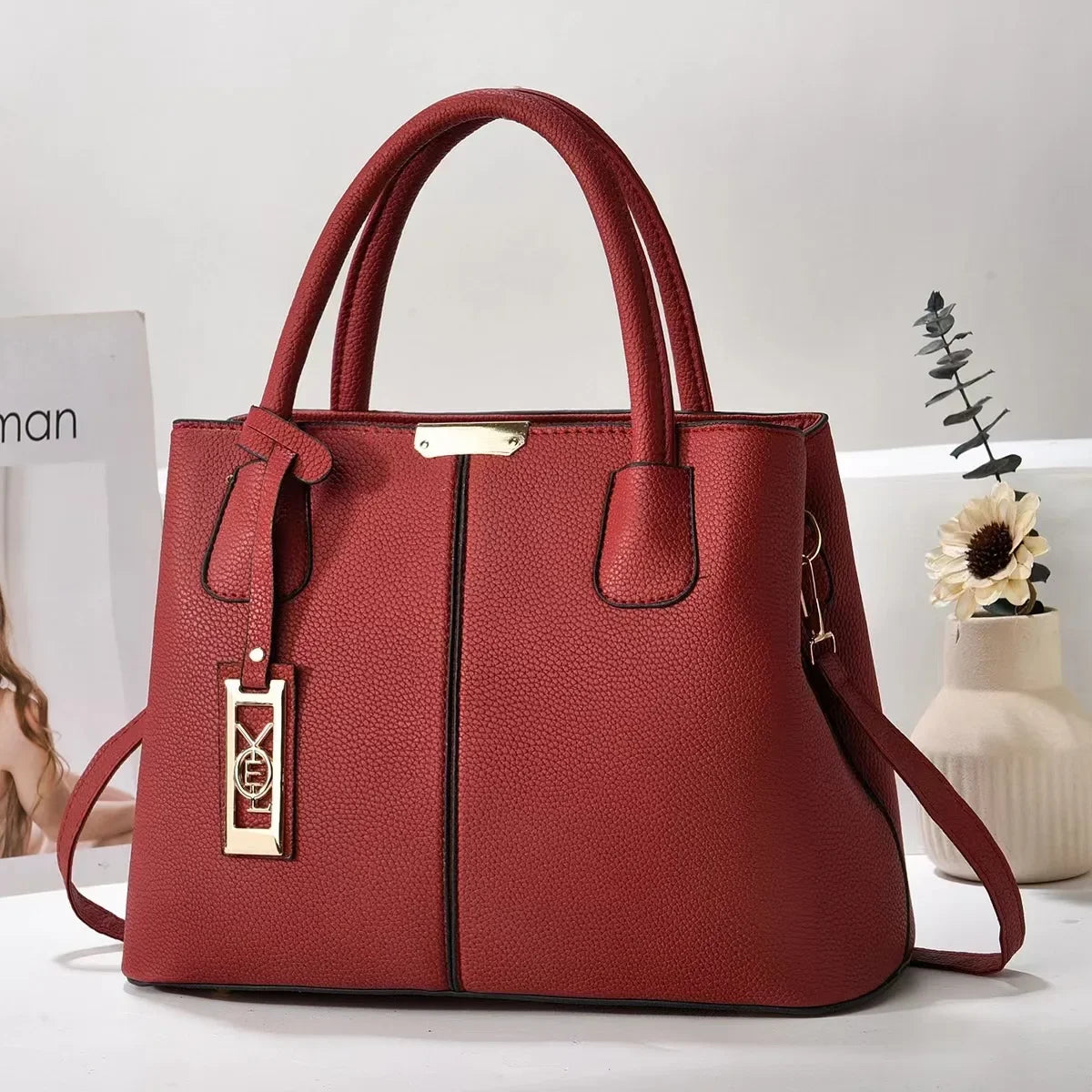 Red faux leather structured tote bag with gold hardware and zip closure for everyday use.