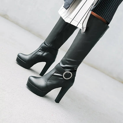 Black faux-leather knee-high platform boots with high block heels and a side buckle strap detail.