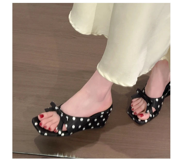 Black polka dot wedge sandals with a front bow and cushioned insole for casual wear.