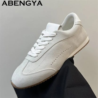 Light gray suede lace-up casual sneaker with white laces and a ridged brown rubber sole.