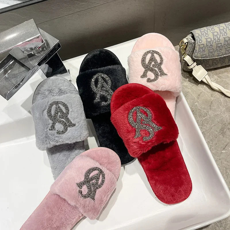 Plush grey, black, red, and pink slippers with rhinestone logos and non-slip soles for cozy home wear.