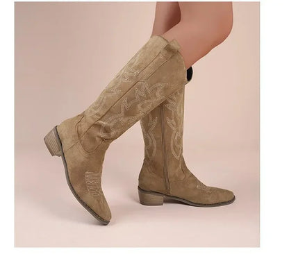 Tan faux suede tall western cowboy boots featuring ornate white stitching, pointed toes, and block heels.