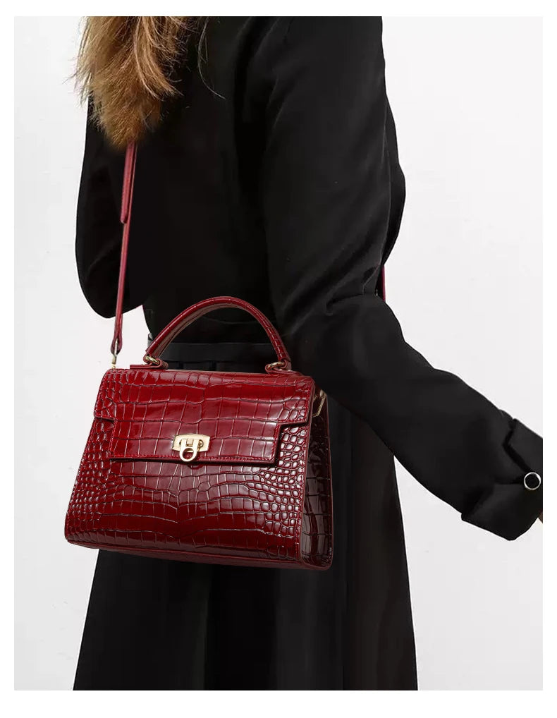 Glossy red leather handbag with crocodile pattern, top handle, flap closure with gold clasp, and shoulder strap.