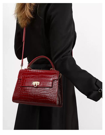 Glossy red leather handbag with crocodile pattern, top handle, flap closure with gold clasp, and shoulder strap.