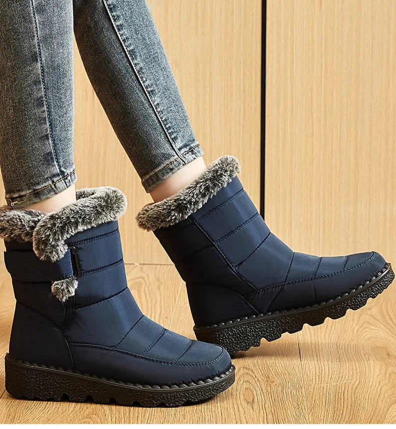 Blue waterproof winter snow boots with fur trim, low heels, and black lug soles, paired with blue jeans.