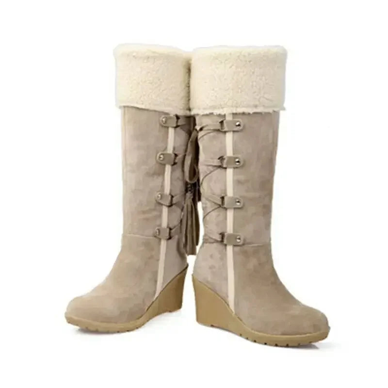 Beige suede knee-high wedge snow boots with white shearling cuffs, side lacing with loops, and a tasseled zipper.