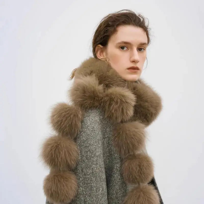 Brown faux fox fur scarf with multiple fluffy pom-poms along the edges, worn around the neck by a woman.