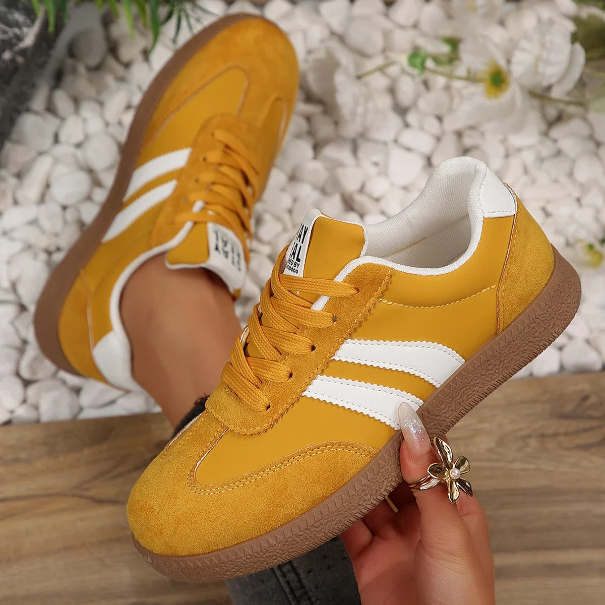 Mustard yellow leather slip-on sneakers with white stripes, suede detailing, and brown rubber soles for daily wear.