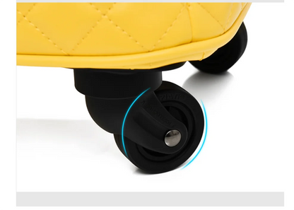 Close-up of a yellow quilted trolley suitcase with black spinner wheels and rotation arrows.