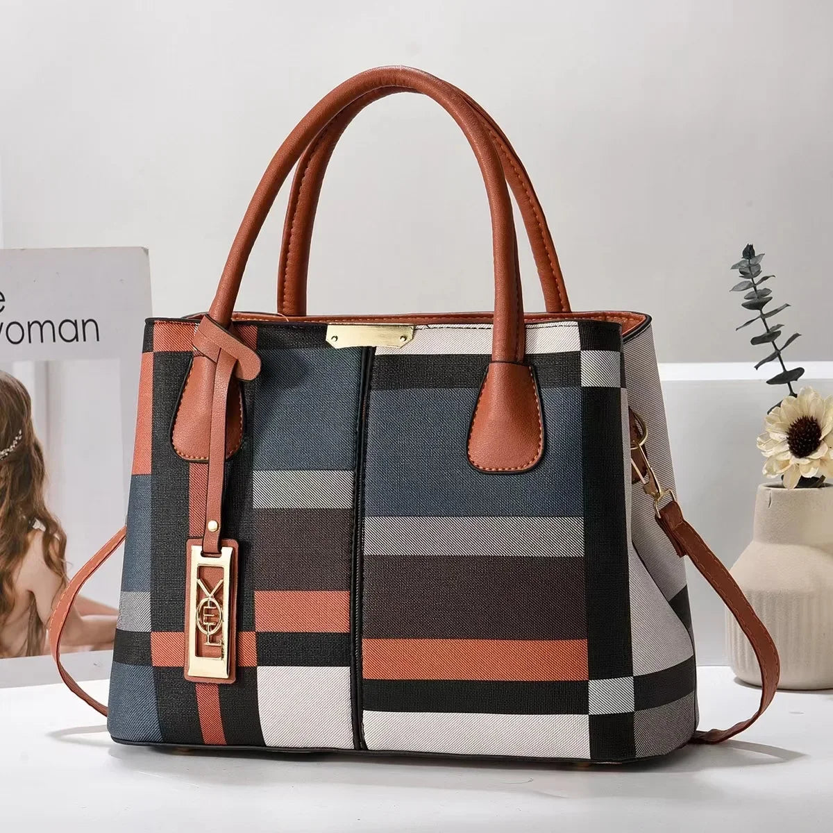 Multi-colored plaid structured tote bag with brown handles and zip closure for everyday use.
