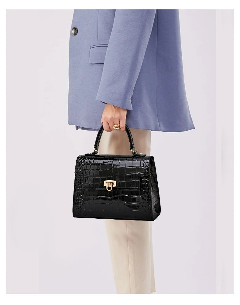 Black lacquer crocodile-pattern leather handbag with a top handle and gold clasp.