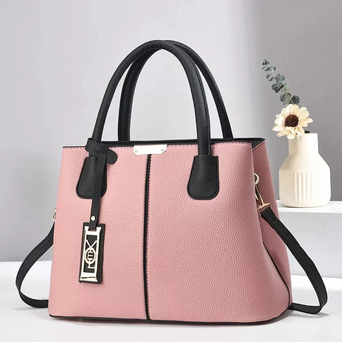Pink faux leather structured tote with zip closure and black handles for everyday use.