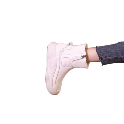 White winter short boot with a thick sole, side zipper, and paneling, worn with dark jeans.