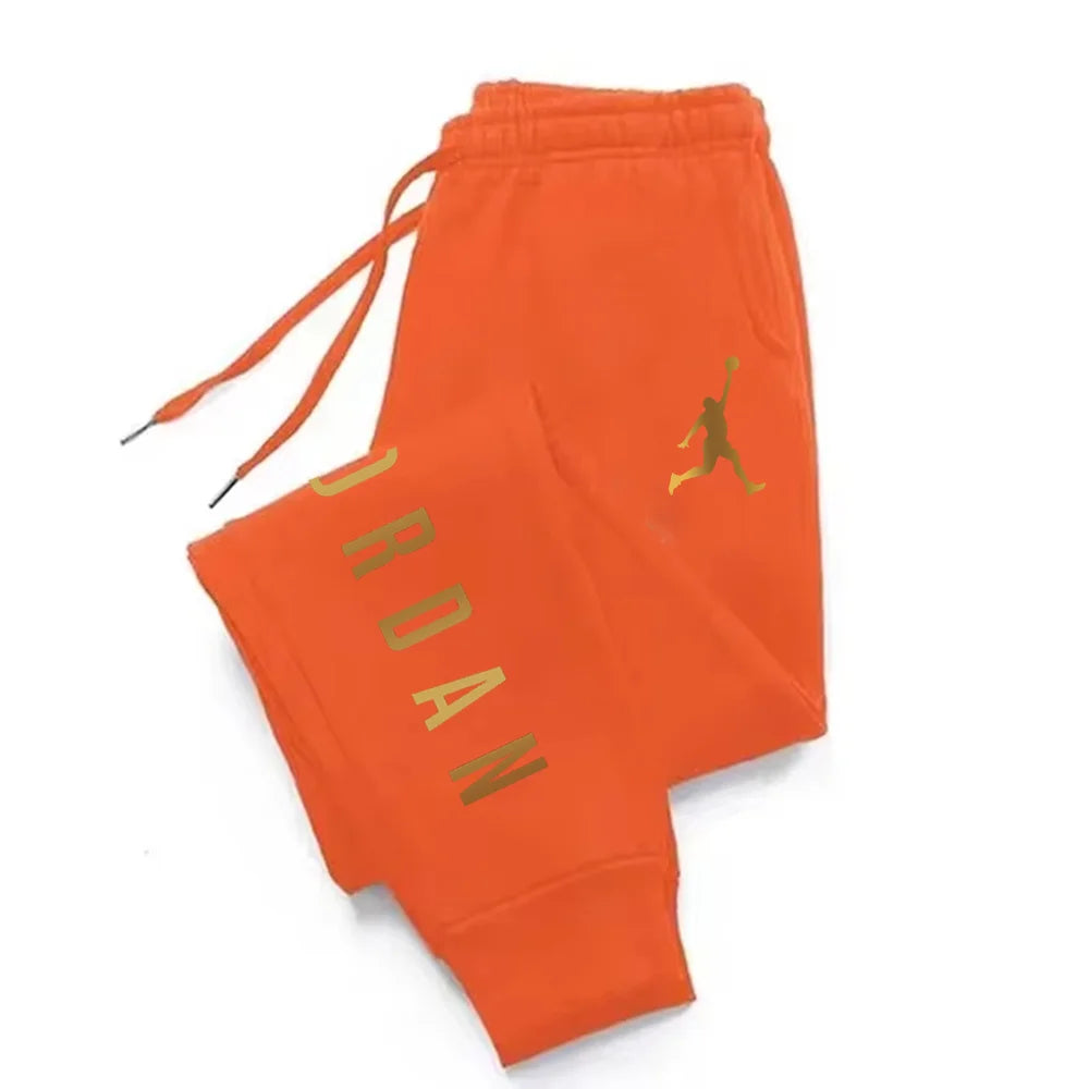 Orange midweight joggers with gold lettering, drawstring waist, and stretchy fabric for athletic wear.
