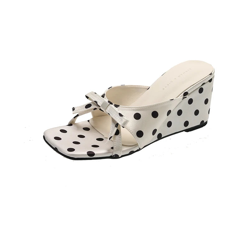 White wedge sandals with black polka dots, bow detail, and cushioned insole for casual wear.