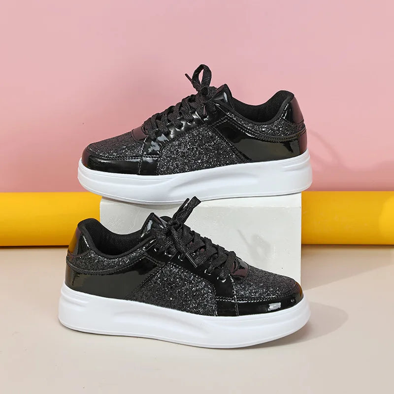 Black lace-up casual sneakers with sparkly glitter panels, patent leather accents, and thick white platform soles.