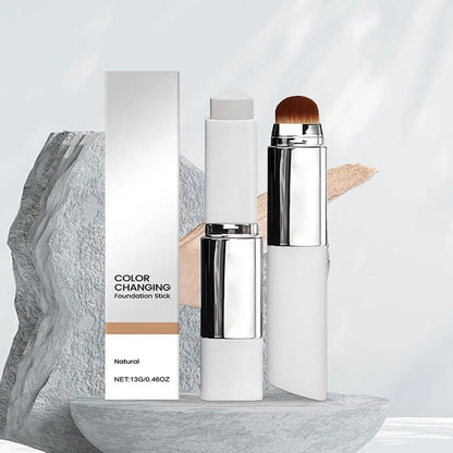Foundation stick with built-in brush and outer packaging box displayed on stone pedestals