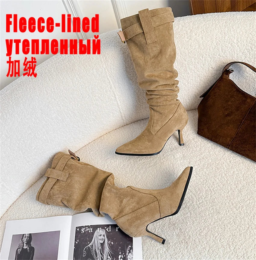 Tan suede slouchy knee-high boots with pointed toes, thin high heels, and buckled straps at the collar.