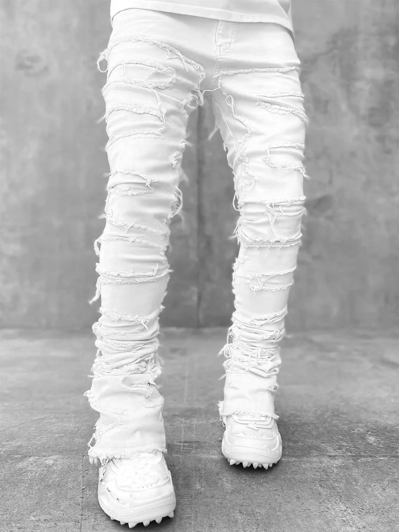 White distressed patchwork jeans with frayed tassel details and a fitted, stretchy design for a casual street style look.