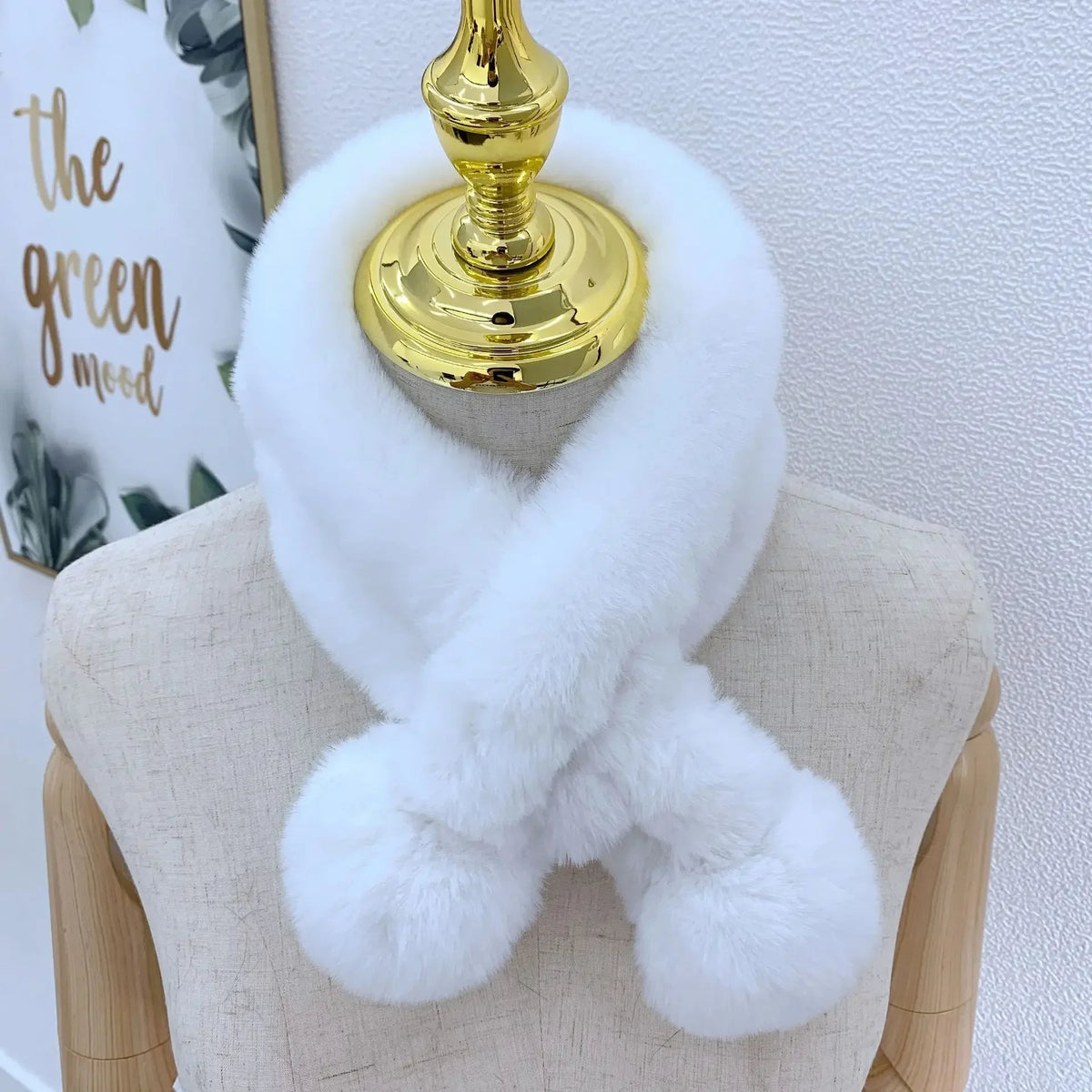 White plush faux fur cross scarf with two end pom-poms on a mannequin.