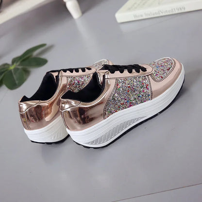 Rose gold metallic sneakers with multicolored glitter panels, black laces, and thick white platform soles.