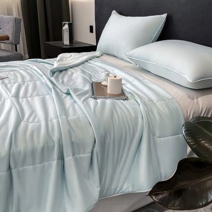 Light blue cooling comforter with a smooth, breathable finish on a bed for hot sleepers.