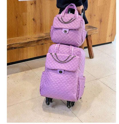 Purple quilted nylon rolling luggage set with chain accent, front pocket, twist-lock closure, and dual wheels.