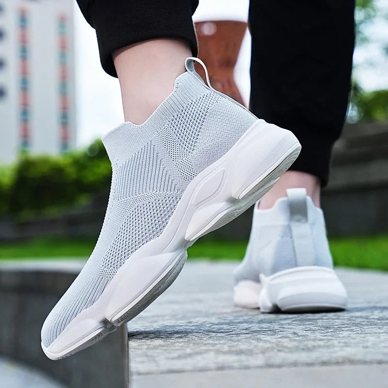 Light grey knit slip-on sneakers with breathable mesh and a cushioned white sole for comfortable casual walking.