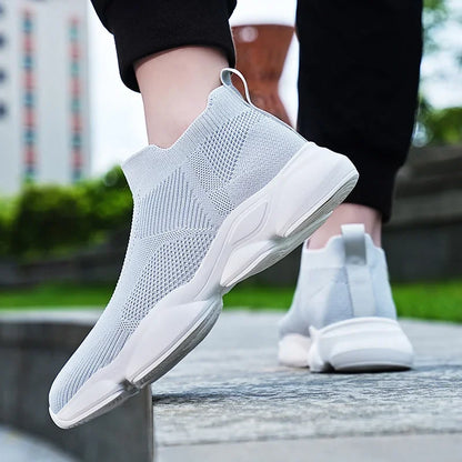 Light grey knit slip-on sneakers with breathable mesh and a cushioned white sole for comfortable casual walking.