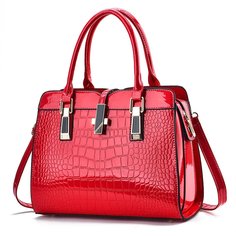 Red patent leather crocodile-pattern tote bag with dual top handles, gold hardware, and a center clasp.