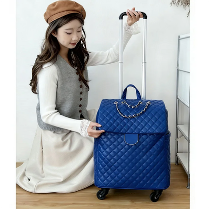 Blue quilted wheeled travel bag with a chain detail, top handle, and extendable trolley handle.