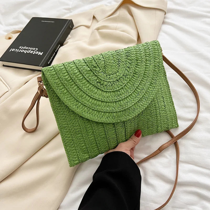Green straw woven envelope crossbody bag with an adjustable strap for beach outings.