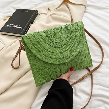 Green straw woven envelope crossbody bag with an adjustable strap for beach outings.