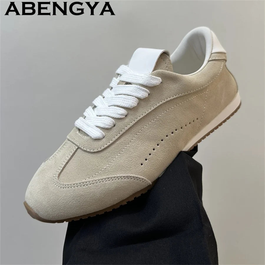 Beige suede lace-up casual sneaker with white laces, white tongue, perforated side detail, and flat rubber sole.